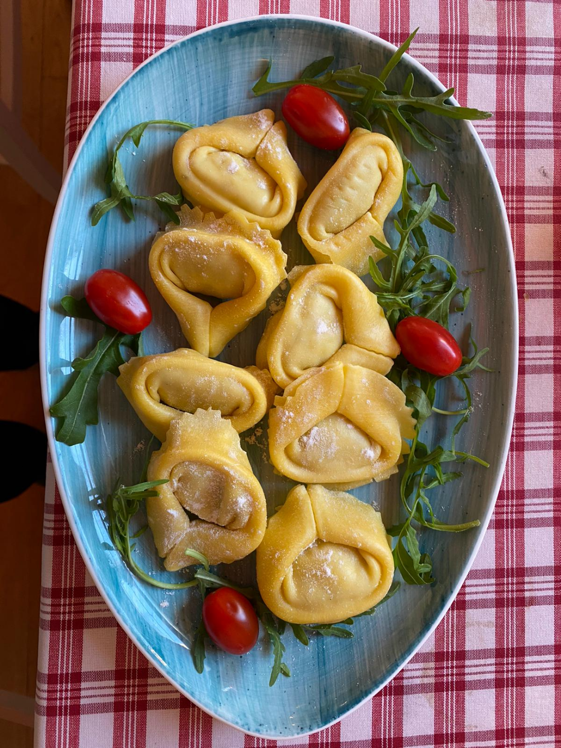 Hausgemachte Tortelloni gefüllt mit Ziegenkäse und Rosmarin in Balsamico Sauce , getrockneten Tomaten, karamellisierten roten Zwiebeln und Rucola Häubchen
